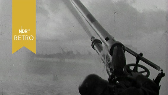 Löschkanone an Bord eines Feuerlöschbootes spritzt Wasser über die See (1963) © Screenshot 
