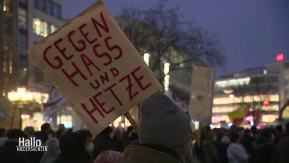 Eine Person mit einem Plakat bei einer Demonstration. © Screenshot 