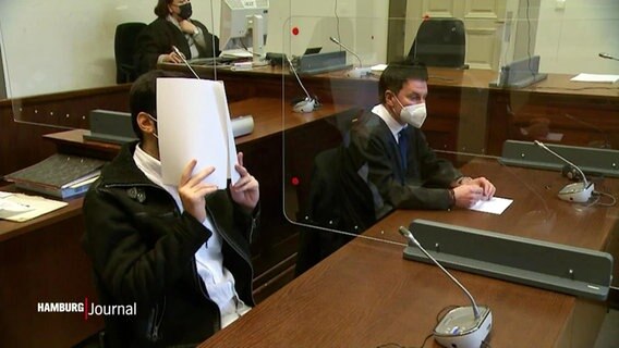 Angeklagter vor Gericht, er hält sich Papier vor das Gesicht. © Screenshot 