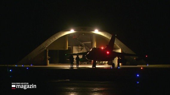 Szene in der Dunkelheit: Ein Torpedo vor einem beleuchteten Hangar. © Screenshot 