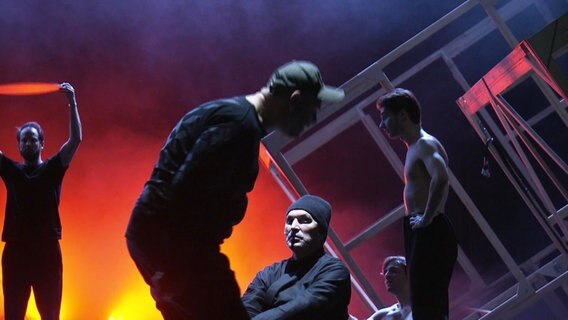 Bühne mit vier Männern in dunkles Licht getaucht. © Screenshot 