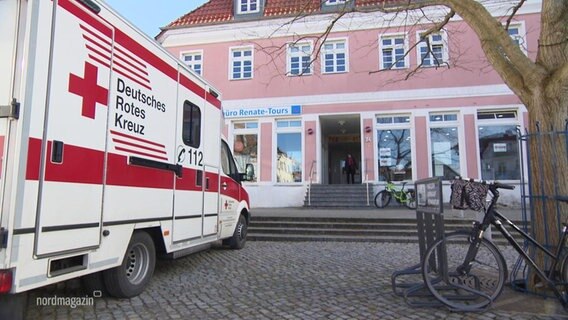 Ein Wagen des Roten Kreuzes steht vor einem Haus. © Screenshot 