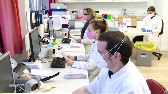 Menschen mit Masken arbeiten in einem Labor. © Screenshot 