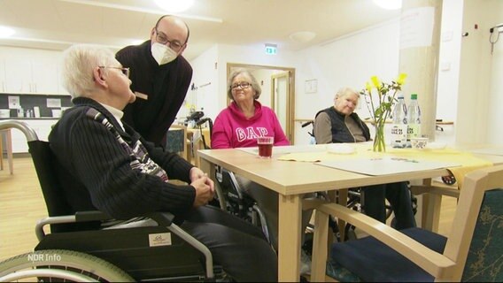 Ein Mann spricht mit Senioren in einem Pflegeheim. © Screenshot 