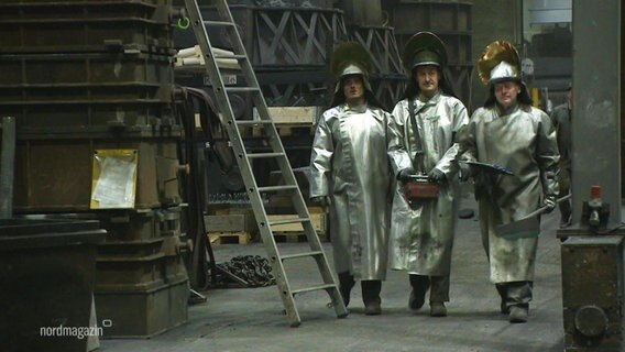 Drei Mitarbeiter in Schutzkleidung in der Eisengießerei Torgelow. © Screenshot 