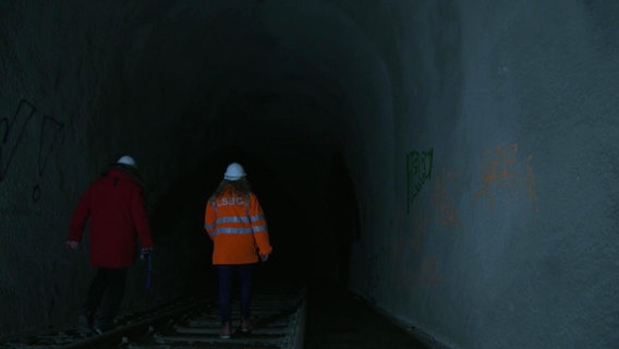 Zwei Menschen in Schutzkleidung gehen durch den Altonaer "Schellfischtunnel". © Screenshot 