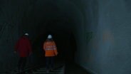 Zwei Menschen in Schutzkleidung gehen durch den Altonaer "Schellfischtunnel". © Screenshot 