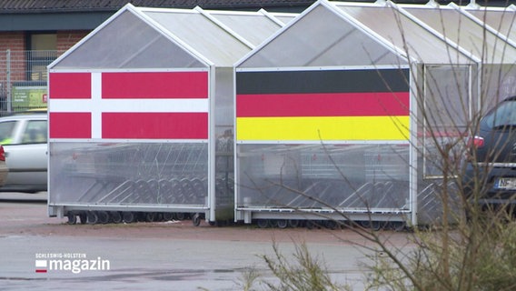 Eine deutsche neben einer dänischen Flagge vor einem Supermarkt. © Screenshot 