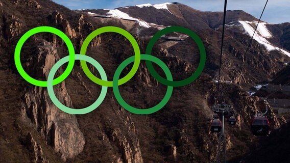 Grüne Olympische Ringe an einem braunen Berg. © Screenshot 