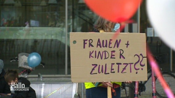 Ein handgeschriebenes Schild auf dem gefragt wird: "Frauen und Kinder zuletzt?" © Screenshot 