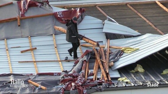 Jemand steht auf einem vom Sturm zerstörten Dach © Screenshot 