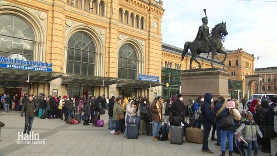 Vor Hannovers Hauptbahnhof steht eine lange Menschenschlange © Screenshot 
