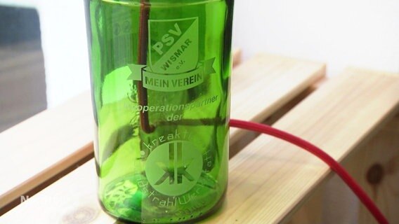 Auf einer Grünglasflasche sind mehrere Logos mit Sandstrahltechnik aufgetragen. © Screenshot 