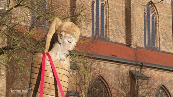 Die riesige Frauen-Skulptur vor einer Kirche © Screenshot 