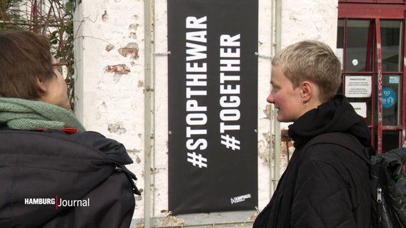 Two people stand in front of a table "# Stop the War" AND "#Together" reads © Screenshot 