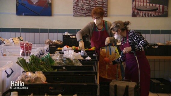 Zwei Frauen packen Tüten aus einer Reihe von Lebensmittelkisten. © Screenshot 