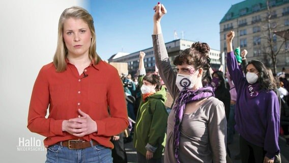 Reporterin Katrin Kampmann steht vor einem Bild von Frauen, die ihre Fäuste in die Luft strecken. © Screenshot 
