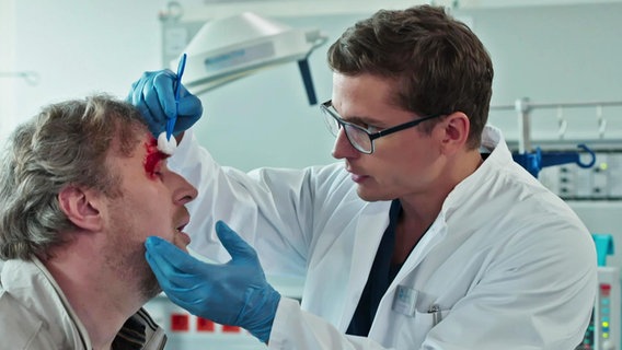 Ein Arzt verarztet die Wunde eines Mannes. © Screenshot 