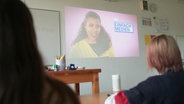 NDR Presenterin Lia Gavi erscheint auf einem Whiteboard vor Schülern. © NDR 