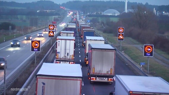 Several trucks backed up in one direction on a highway.  © screenshot 