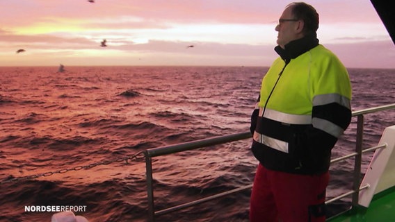 Ein Mann steht an Bord eines Schiffes und schaut aufs Meer. © Screenshot 