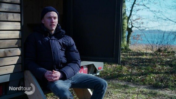 Georg Mentz sitz vor seiner mobilen Sauna. © Screenshot 
