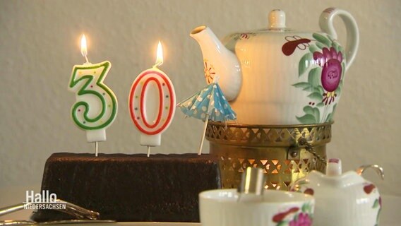 Kerzen in Form einer 30 auf einem Kuchen neben einer Teekanne © Screenshot 