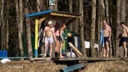 Männer und Frauen in Badebekleidung an einem See in Russland. © Screenshot 