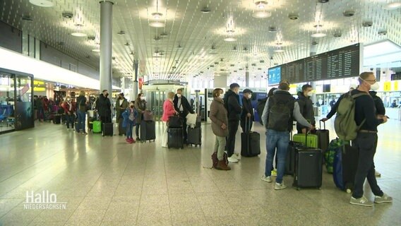 Eine lange Menschenschlange am Flughafen. © Screenshot 