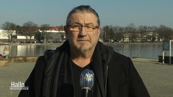 Ein Mann spricht in ein Mikrofon. © Screenshot 