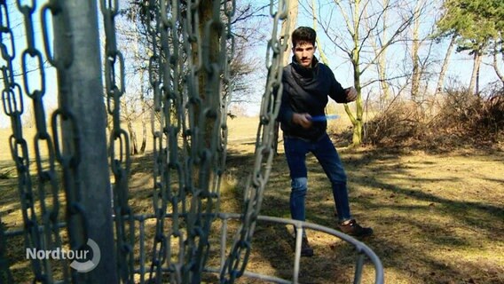 Ein junger Mann spielt Discgolf. © Screenshot 
