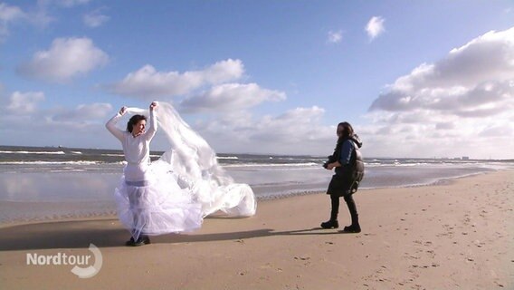 Photoshooting am Strand mit einer Frau im Brautkleid. © Screenshot 