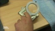 Eine Hand hält eine Lupe über ein digitales Speichermedium. © Screenshot 