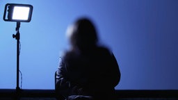 Eine anonymisierte Frau sitzt vor einem Scheinwerfer und gibt ein Interview. Eine anonymisierte Frau sitzt vor einem Scheinwerfer und gibt ein Interview. © Screenshot