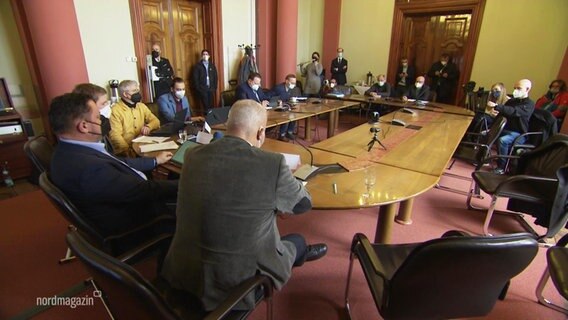 In einem Saal sitzen mehrere Politiker in Anzügen und geben eine Pressekonferenz © Screenshot 