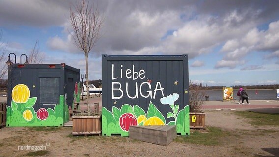 Auf zwei Containern im Rostocker Hafen sind Blumen zu sehen und die Schrift "Liebe BUGA". © Screenshot 