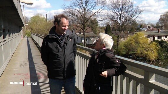 Ein Mann und eine Frau unterhalten sich auf einer Brücke © Screenshot 
