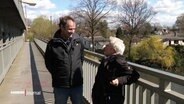 Ein Mann und eine Frau unterhalten sich auf einer Brücke © Screenshot 