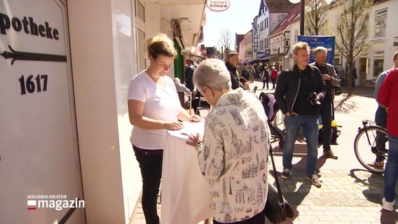 Menschen in der Fußgängerzone unterschreiben eine Petition. © Screenshot 