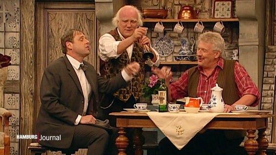 Drei Schauspieler des Ohnsorg Theaters prosten sich in einer Szene zu. © Screenshot 