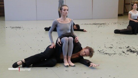 Eine Ballett-Tänzerin sizt bei einer Figur auf ihrem seitwärts auf dem Boden liegenden Mittänzer. © Screenshot 