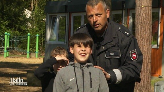 Zwei Kinder mit einem Polizisten © Screenshot 