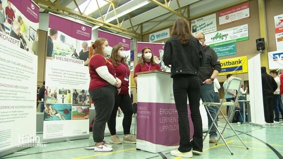 Ein Mädchen besucht einen Stand auf einer Berufsmesse. © Screenshot 