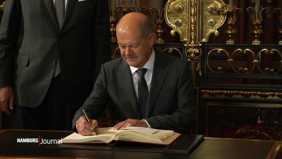 Olaf Scholz trägt sich in das Goldene Buch des Übersee-Clubs ein. © Screenshot 
