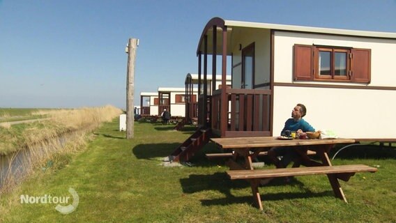 Reporter Peter Jagla auf einem Campingplatz vor einem Zirkuswagen. © Screenshot 