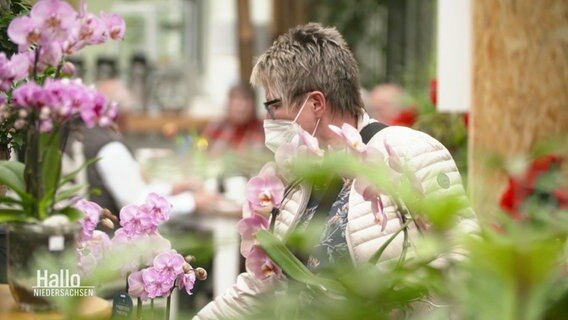Eine Frau schaut sich Blumen in einer Gärtnerei an. © Screenshot 