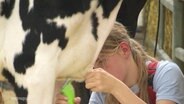Eine Jungzüchterin schert einer Kuh die Haare. © Screenshot 