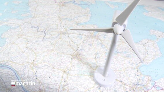 Ein Modell-Windrad steht auf einer Landkarte. © Screenshot 
