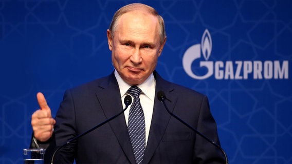 Der russische Präsident Wladimir Putin vor einer Gazprom-Wand.  