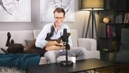 Dr. Wimmer schmust mit einem Hund auf der Couch. © Screenshot 